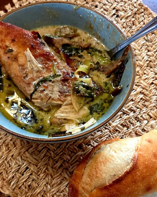 Early spring braise with chicken, ramps, fiddleheads and Lion's Mane in anchovy white wine cream sauce served in a rustic bowl with crusty bread