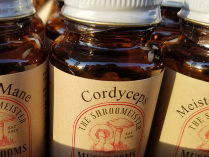 Close up view of glass bottle containing capsules labeled Cordyceps Mushroom Supplements with a red and beige color scheme.